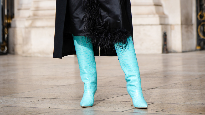 Woman wearing blue crocodile boots.