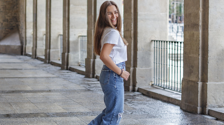 A woman smiling with baggy ripped jeans and a white tee