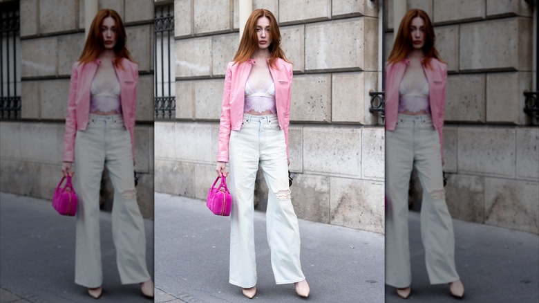 Woman wearing white flared jeans and a pink jacket