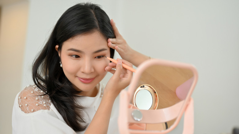 woman drawing eyeliner