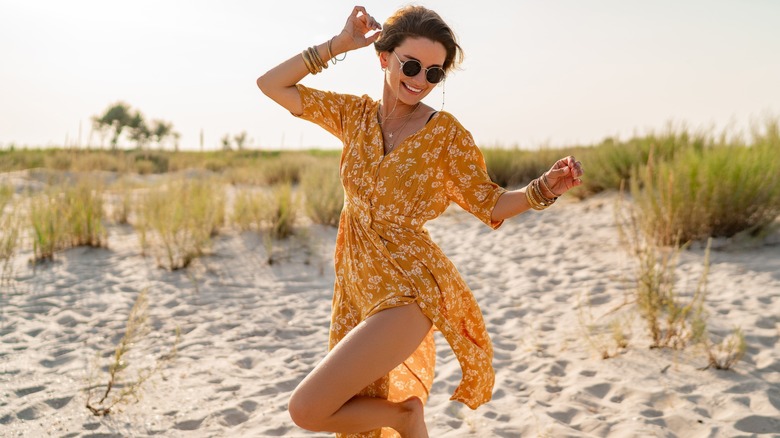Woman in yellow dress, standing on a beach
