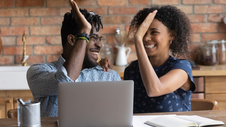 high-fiving couple with laptop