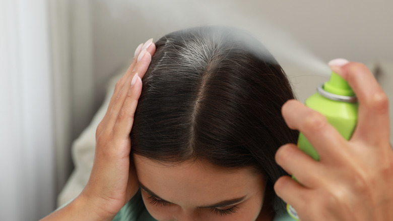 Woman spraying roots with dry shampoo 