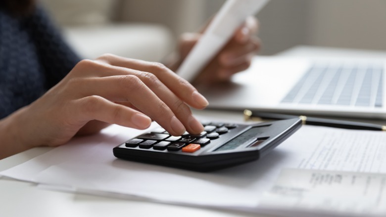 Hand typing on a calculator