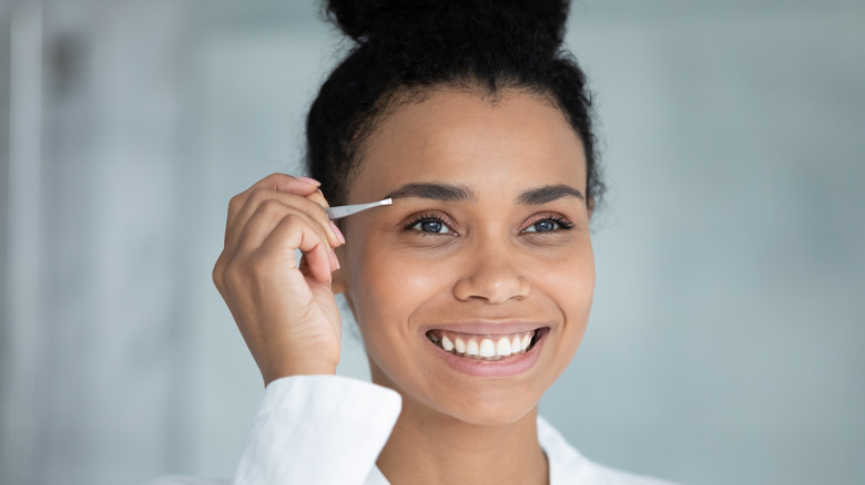 Woman tweezing with hair growth.