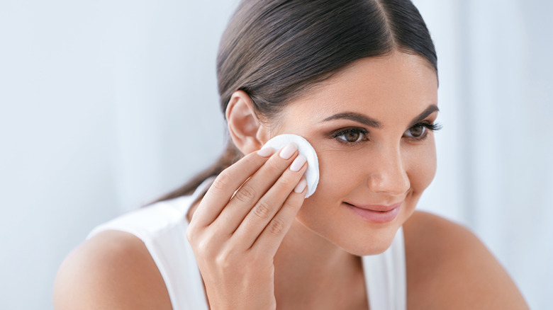Woman using a cotton round to wipe off face