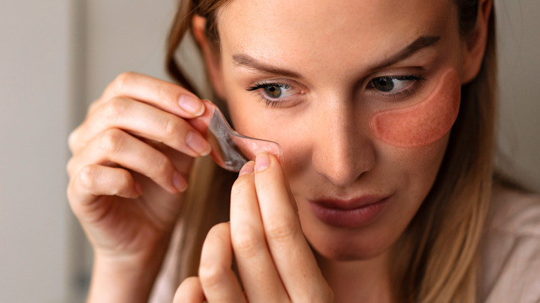 Woman applying hydrogel mask patches to face