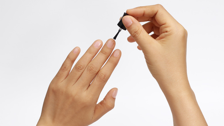 person applying clear nail polish