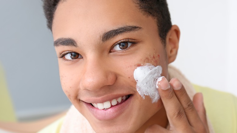 boy applying cream to cheek