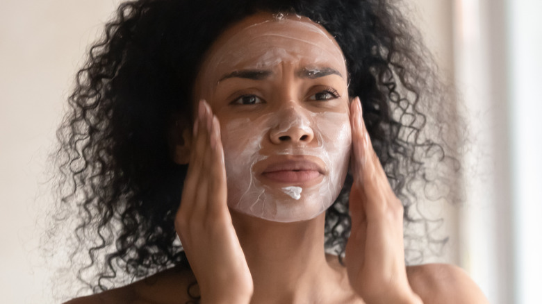 woman applying clay mask to face