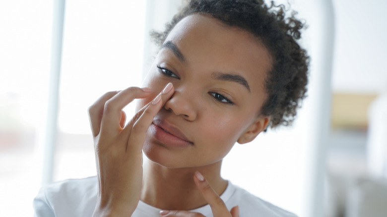 A woman applying eye cream in a well-lit area