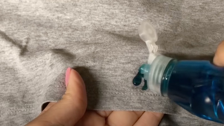 A woman applying Dawn dish soap to a stained sweater