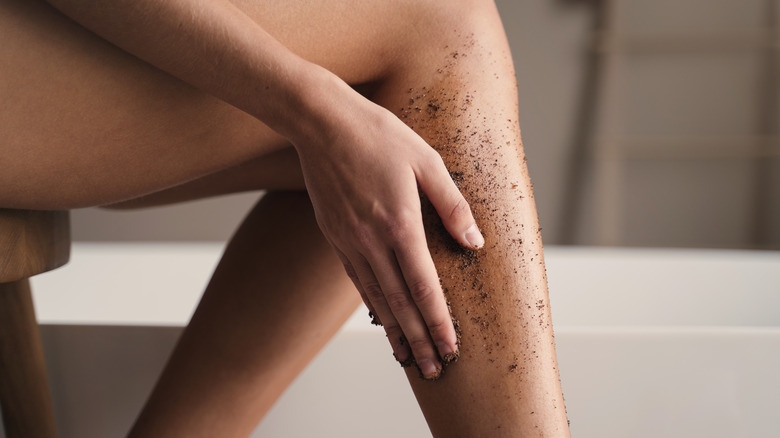 woman exfoliating legs with scrub