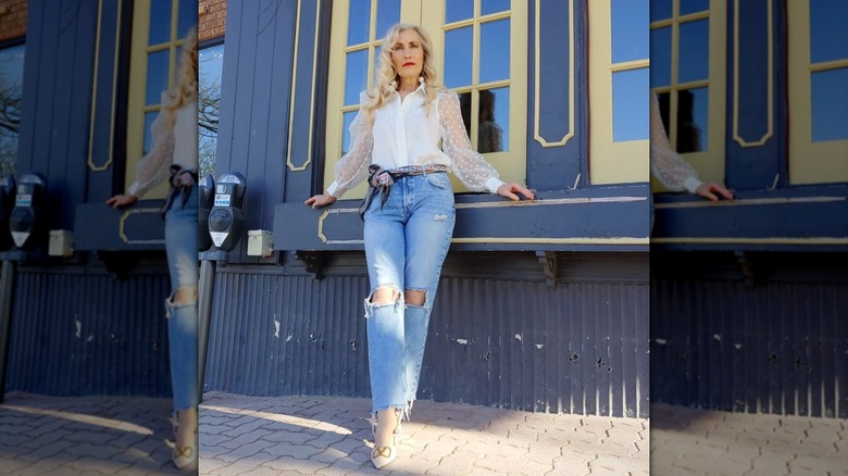 An older woman with blond hair posing with distressed cropped ankle-length jeans