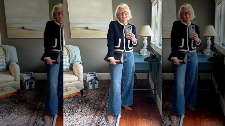 A woman posing in flared jeans and a blue-and-white cardigan