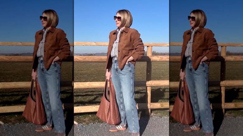 An older woman posing with straight-leg jeans and a suede jacket