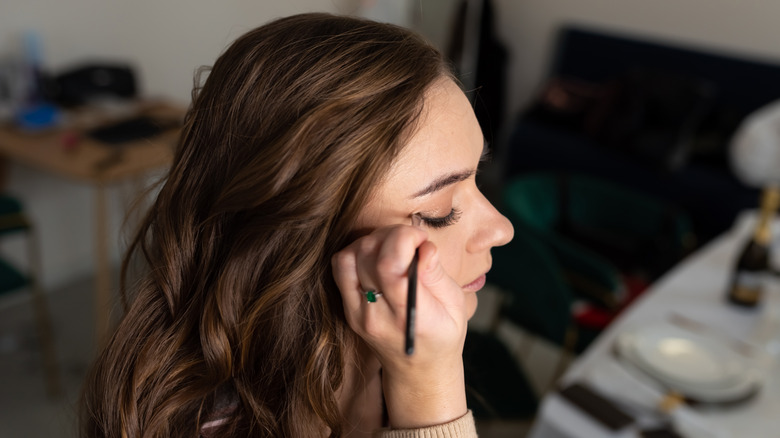 Woman applying liner to her eyes