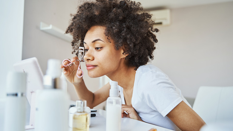 Woman curling her eyelashes