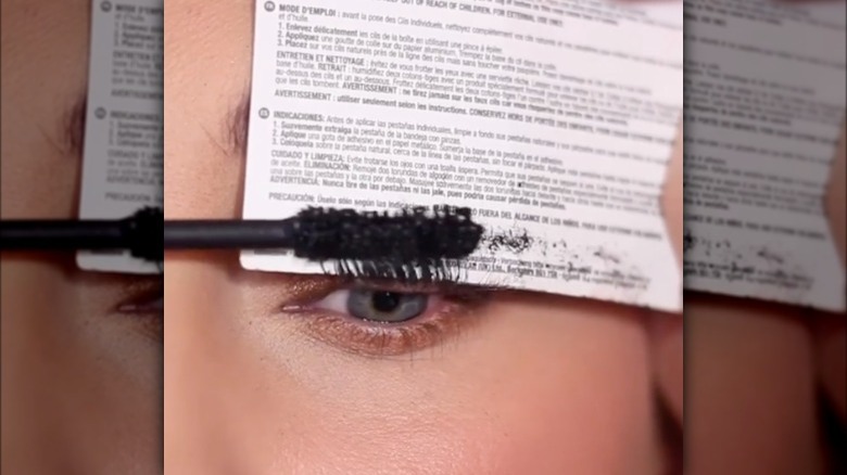 Woman applying mascara with card