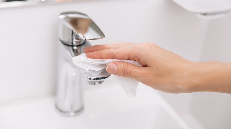hand wiping down sink with a towel