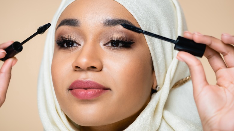 person holding two mascara wands 