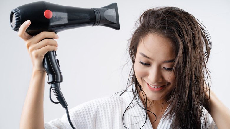 smiling woman using blow dryer