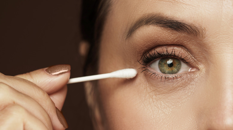 Girl holding cotton swab near her eyes