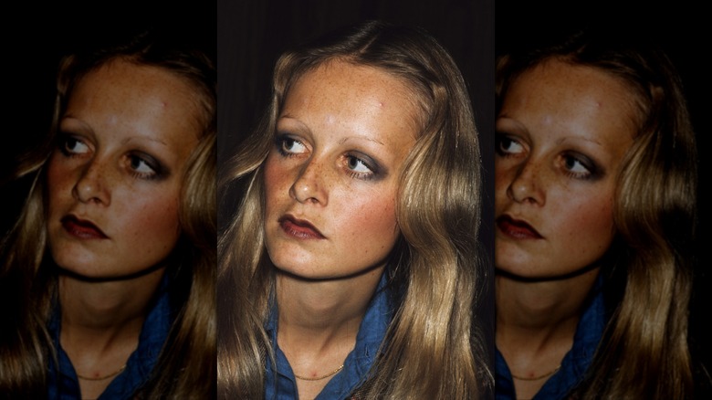Twiggy looks to the left wearing a blue shirt and smoky eye makeup