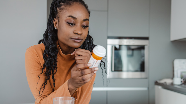 woman looking at pill bottle