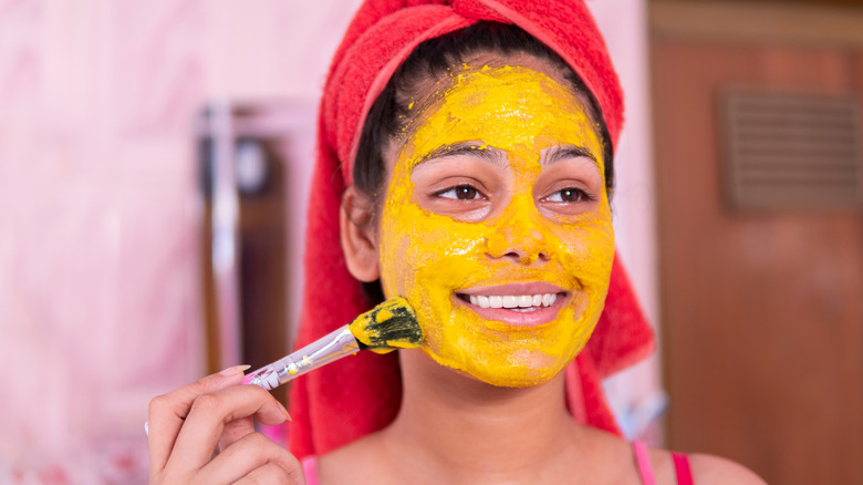 Woman applying turmeric mask