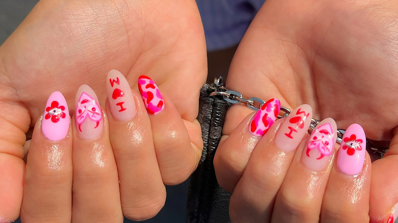 Nail art with hearts, dots, and initials