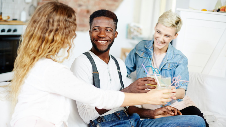 Two women, man toasting on couch