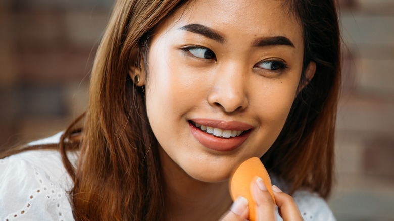 Woman applies setting powder with sponge