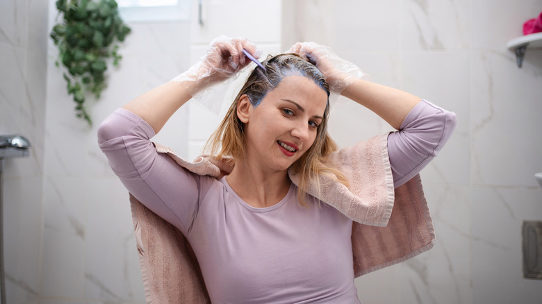 A woman dyeing her own hair at home