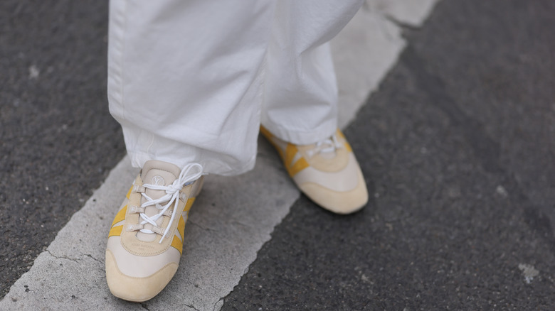 A person wearing Louis Vuitton beige sneakerinas