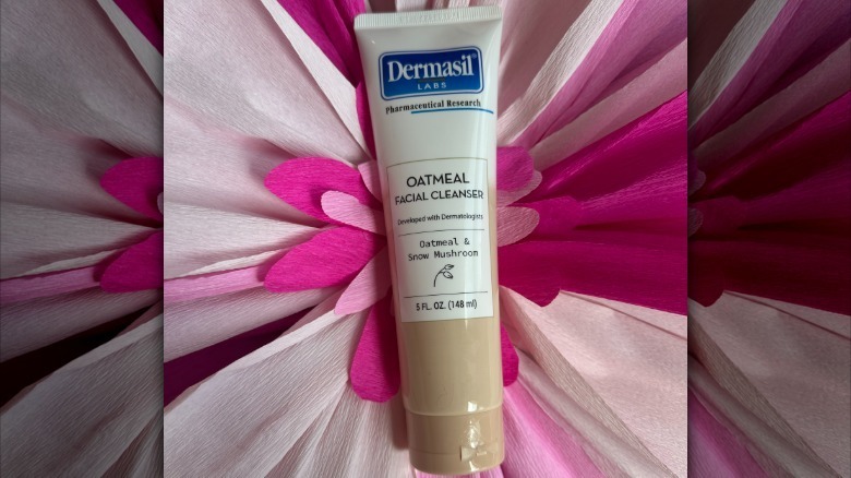 A bottle of Dermasil Labs' Oatmeal Facial Cleanser on a floral backdrop