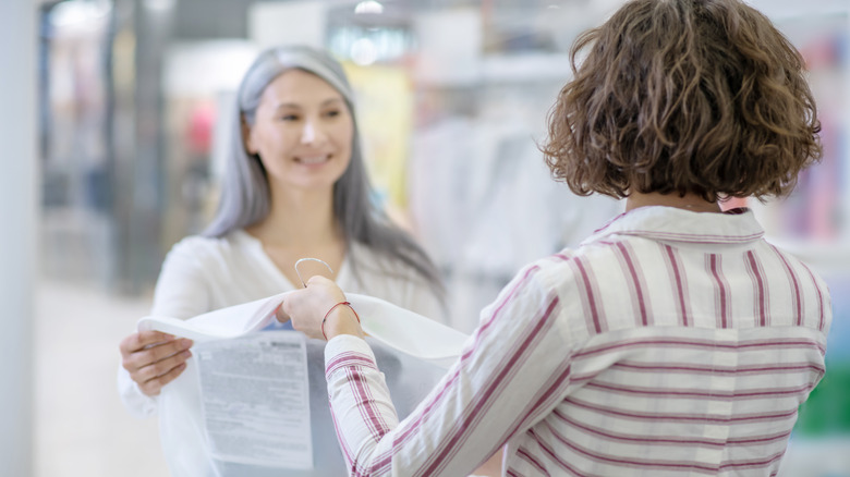 woman handing over dress