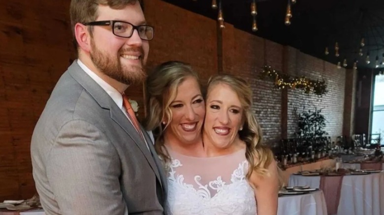 Josh Bowling stands next to Abby and Brittany Hensel on their wedding day