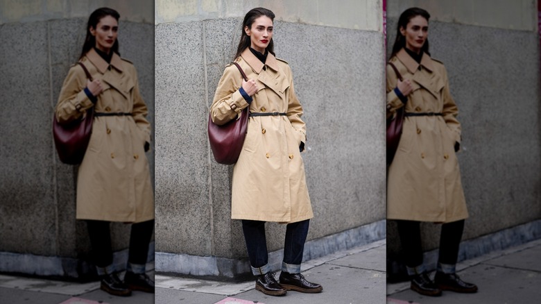 Model wearing cuffed jeans, a trenchcoat, and derby shoes