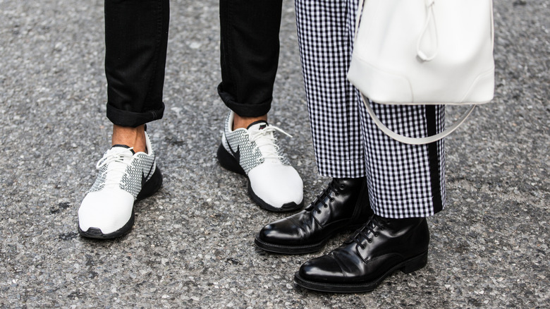 One person wearing sneakers and another wearing black derby shoes