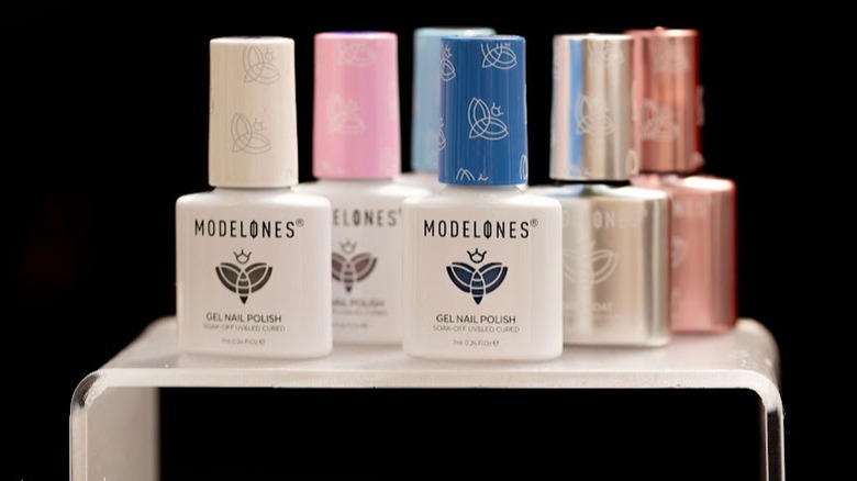 A collection of Modelones gel nail polishes sit on a white stand