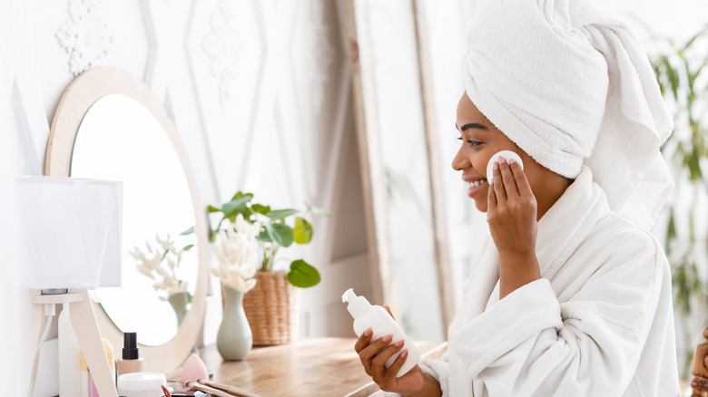 Woman removing makeup in front of vanity