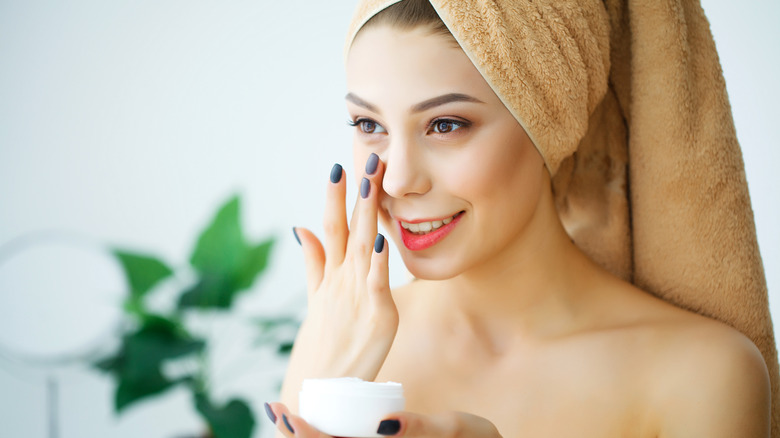 Woman applying moisturizer to face