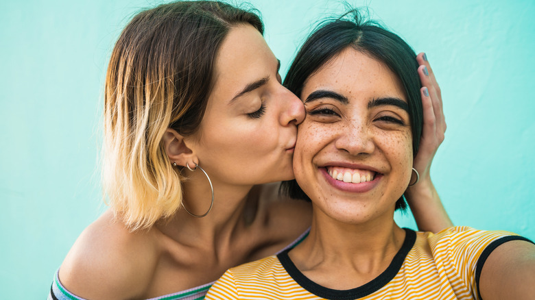 Woman kissing another woman's cheek