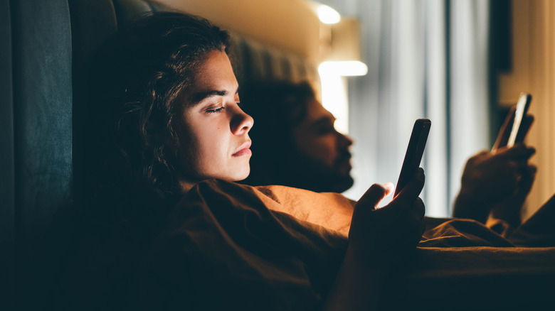 Couple using cellphones in bed