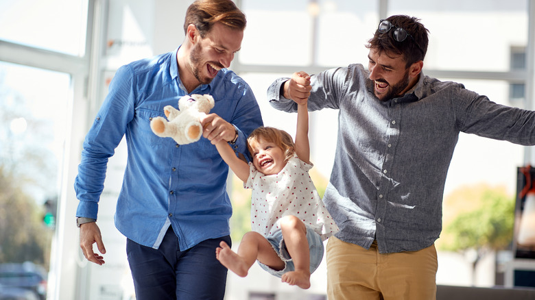 Two fathers playing with child
