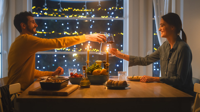 Couple clinking glasses over dinner