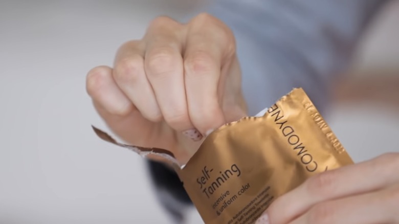 Woman grabbing tanning wipe