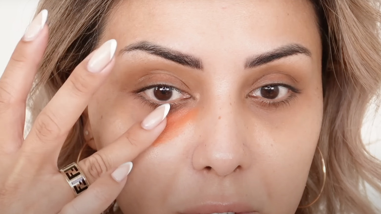 woman applying orange concealer
