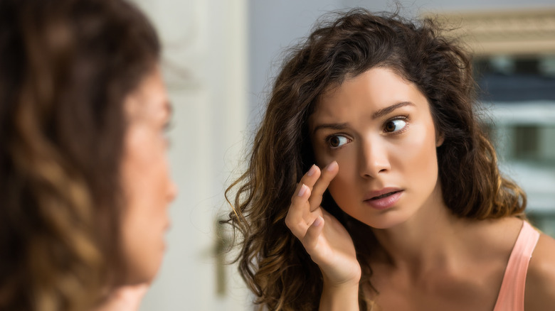 Model examining face in mirror